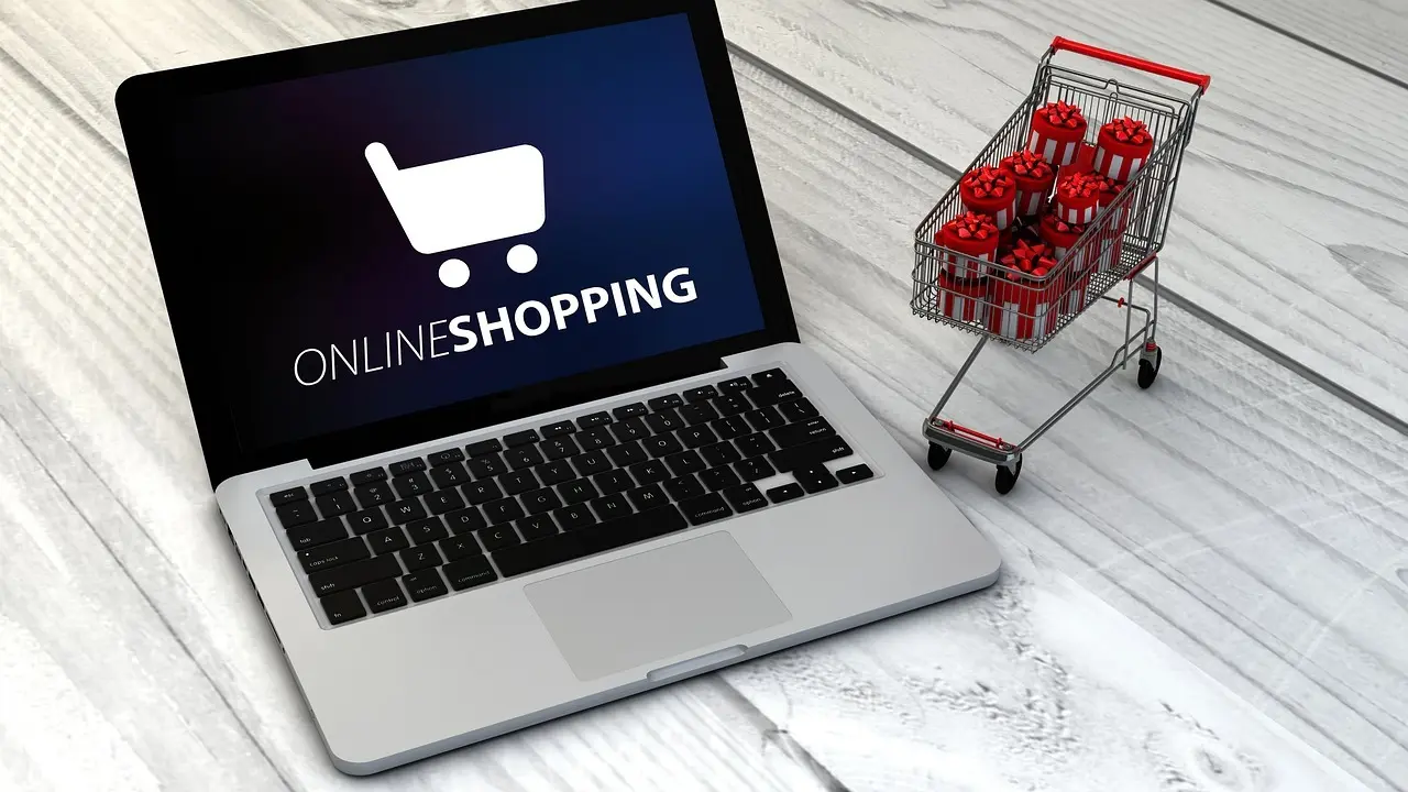 Bærbar computer med online shopping og en lille indkøbsvogn med gaveæsker