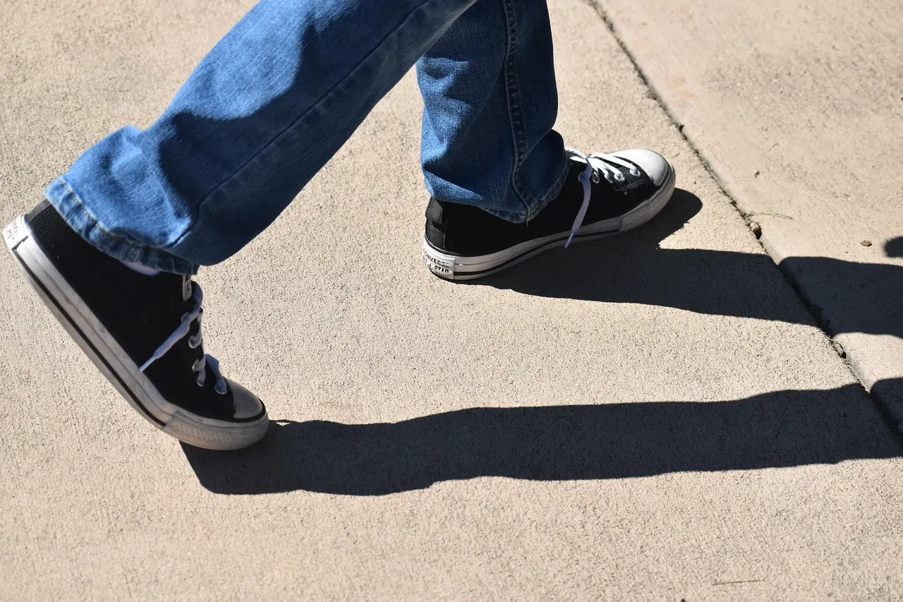 Sorte sneakers og jeans på et fortov